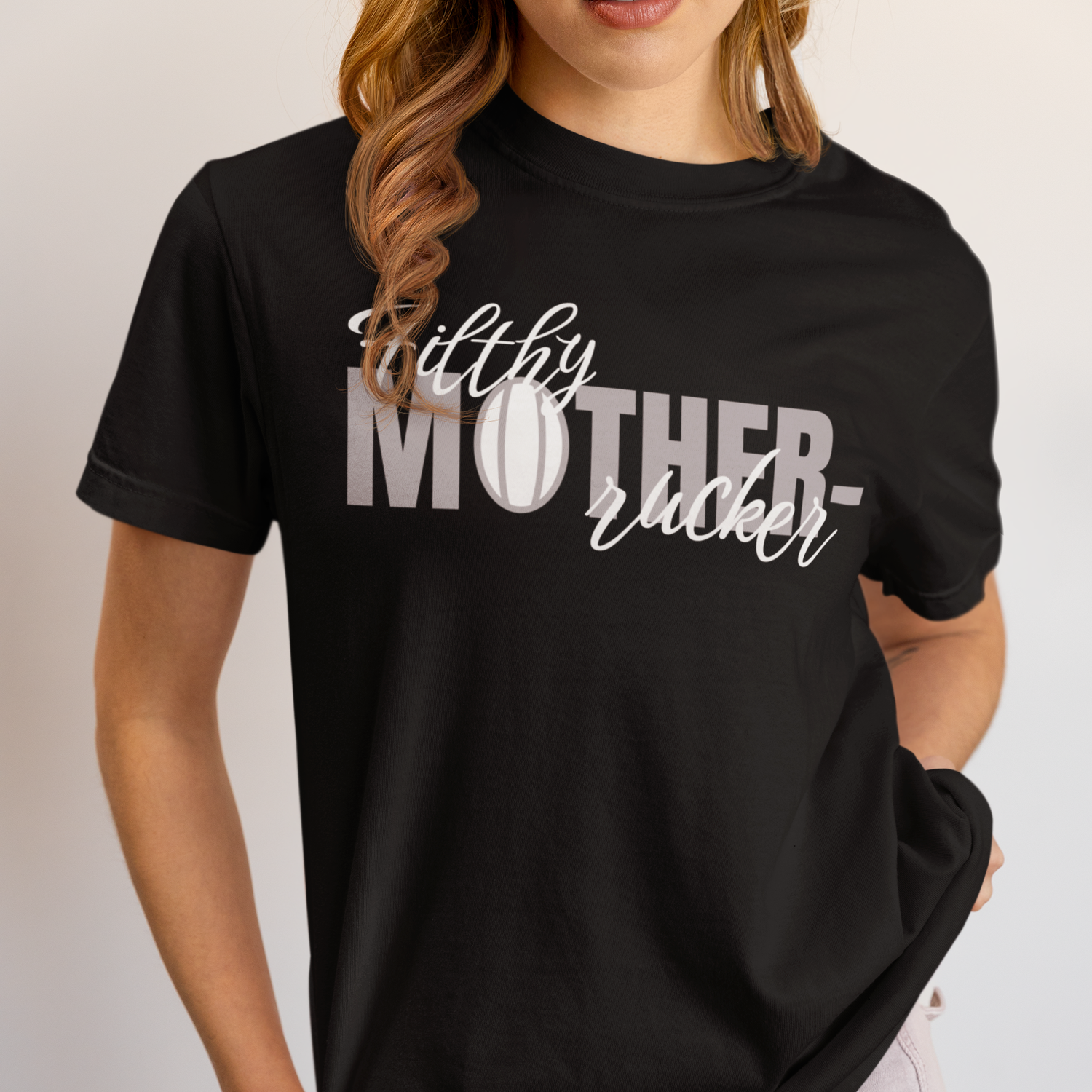 Person wearing a black T-shirt with the phrase "Filthy Mother- [rugby ball image] -rucker" printed on it. A perfect pick if you're looking for great T-shirt gifts for women who love sports and humor.